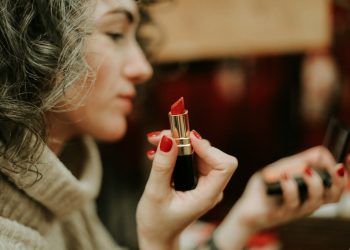 woman in gray sweater holding lipstick